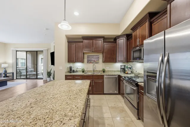 a large kitchen with stainless steel appliances kitchen island granite countertop a refrigerator a stove a sink and dishwasher