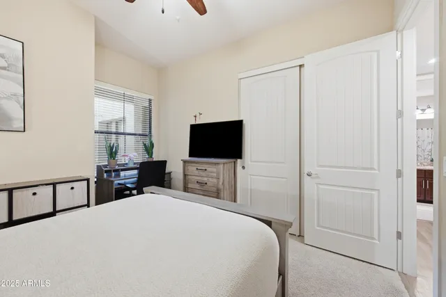 a bedroom with a bed and a flat tv screen on dresser