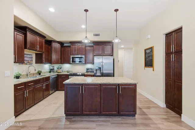 a kitchen with kitchen island granite countertop wooden cabinets and a wooden floor