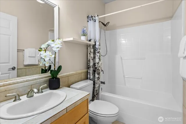 a bathroom with a sink a toilet a mirror and shower