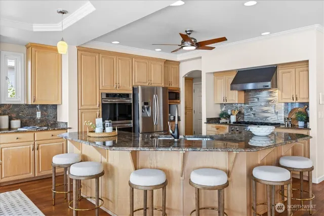 a kitchen with stainless steel appliances granite countertop a table chairs stove and kitchen island