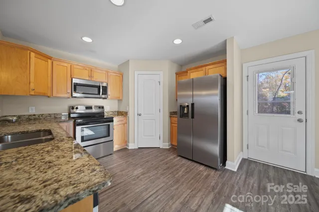 a kitchen with granite countertop a refrigerator and a stove top oven