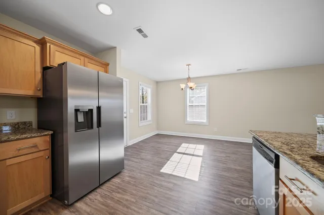a kitchen with stainless steel appliances granite countertop a refrigerator a sink and a stove