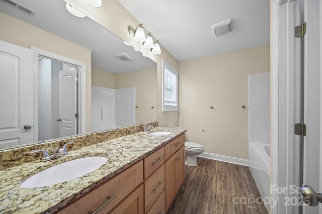 a bathroom with a granite countertop sink a toilet and shower