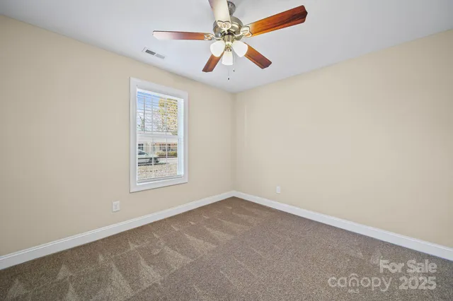 an empty room with windows and fan