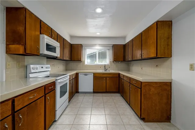 a kitchen with stainless steel appliances granite countertop wooden cabinets a stove top oven a sink and dishwasher