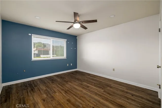 an empty room with wooden floor ceiling fan and windows
