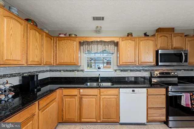 a kitchen with granite countertop a sink and a stove top oven