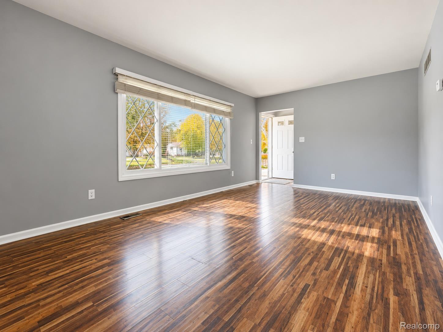 21761 Middlebelt Road Farmington, MI 48336 - Photo 6 of 21 Rich wood-finish flooring, neutral gray wall tones, a large picture window with decorative grilles, and a white paneled front door