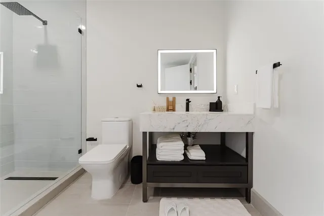 a bathroom with a granite countertop sink a toilet a mirror and shower