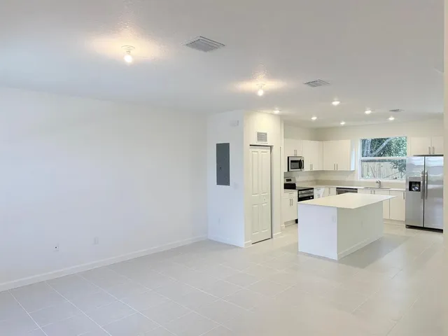 a view of open kitchen with white cabinets and stainless steel appliances