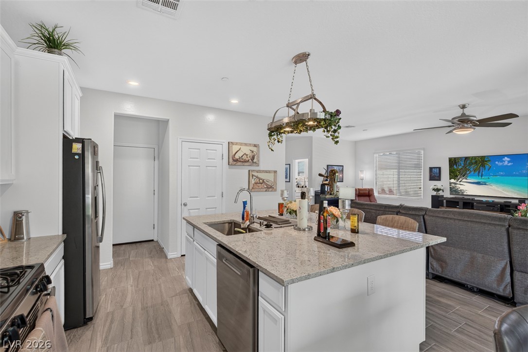 1824 Redland Ridge Street Henderson, NV 89002 - Photo 12 of 69 Granite counters and stainless steel appliances adorn this open-concept kitchen, seamlessly flowing into a comfortable living space.
