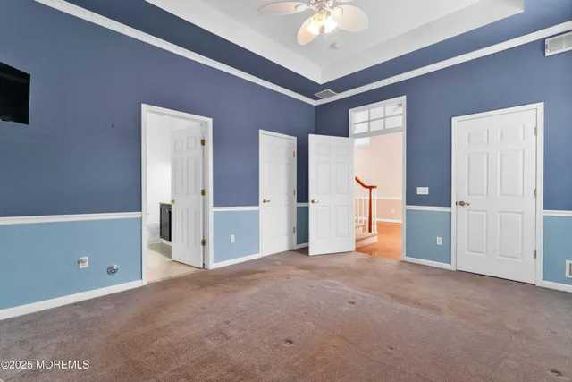 a view of an empty room with chandelier fan