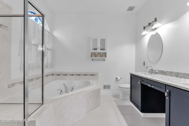 a spacious bathroom with a tub sink mirror and a shower