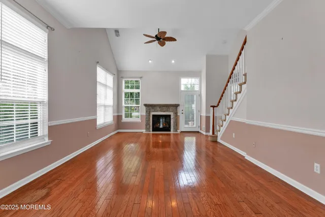 a view of an empty room with wooden floor fireplace and a window