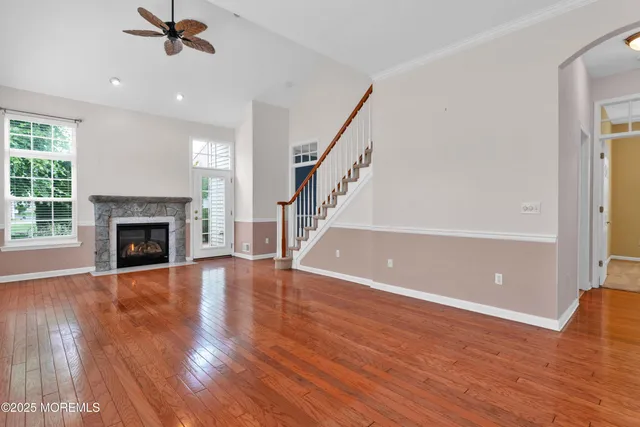 a view of an empty room with wooden floor fireplace and a window