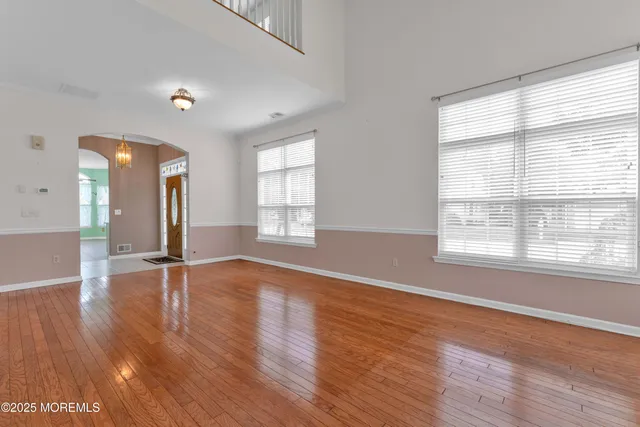 an empty room with wooden floor and windows with curtains