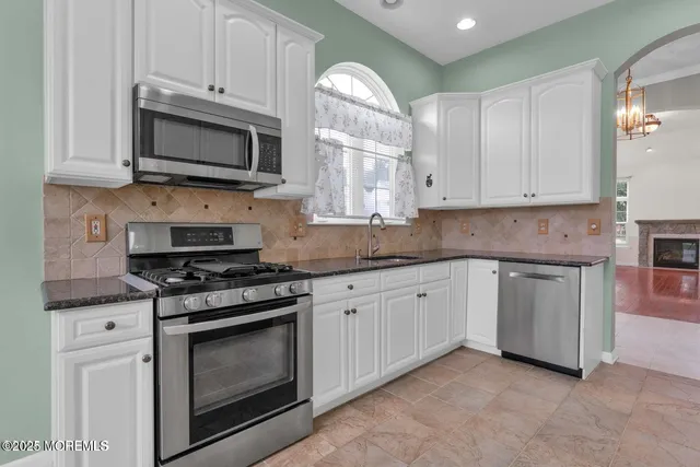 a kitchen with stainless steel appliances granite countertop grey cabinets a stove a sink and a microwave