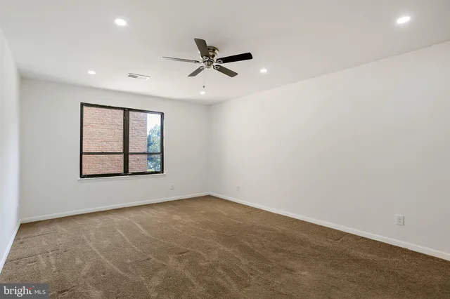 an empty room with windows and fan