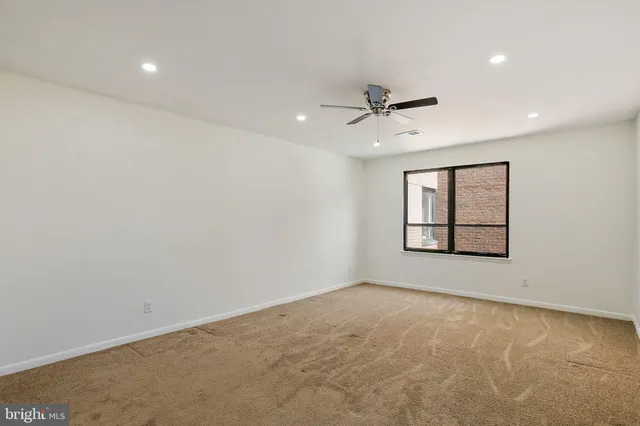 an empty room with windows and fan