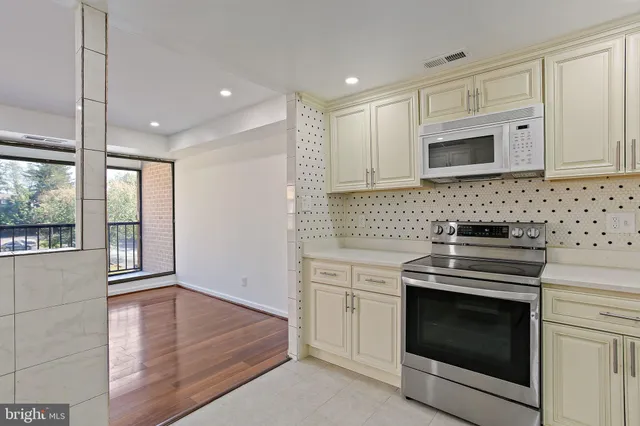 a kitchen with stainless steel appliances granite countertop a stove a sink and white cabinets