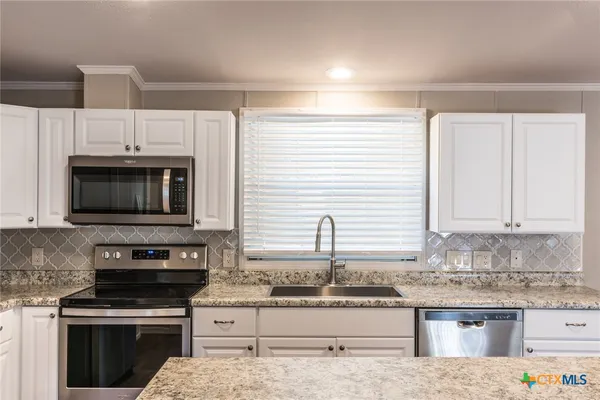 a kitchen with stainless steel appliances granite countertop a stove a sink and a microwave