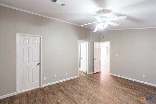 an empty room with wooden floor fan and window