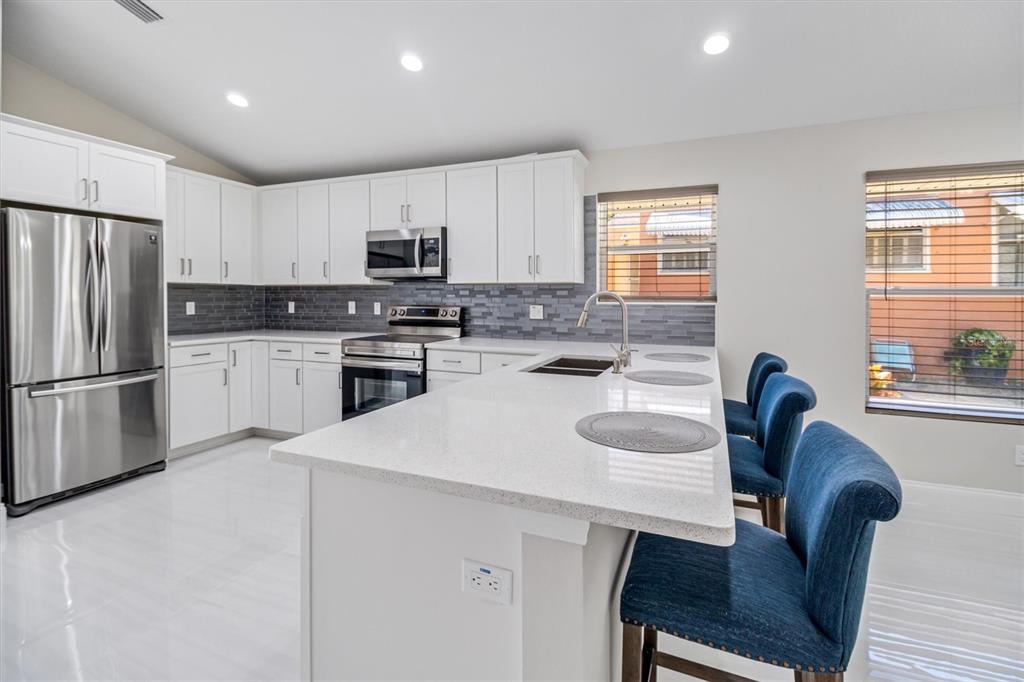 53 Wilmette Avenue Ormond Beach, FL 32174 - Photo 14 of 36 a kitchen with stainless steel appliances granite countertop a stove a sink a refrigerator a dining table and chairs