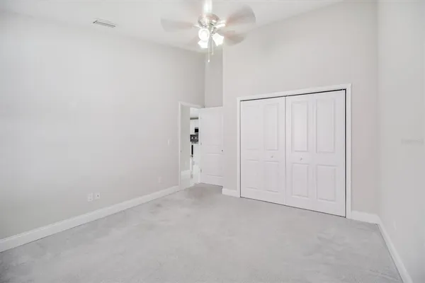 an empty room with a fan & a ceiling fan
