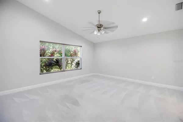 an empty room with windows and ceiling fan