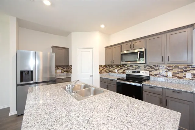 a kitchen with stainless steel appliances granite countertop a refrigerator stove microwave and sink