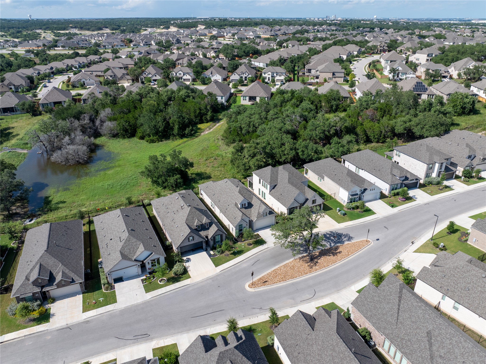 294 Kimble Creek Loop Kyle, TX 78640 - Photo 34 of 40 An aerial perspective reveals a vibrant neighborhood bordered by natural green space and a tranquil pond.
