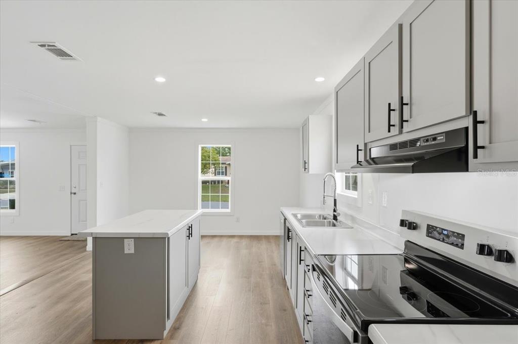 9128 Scepter Avenue Brooksville, FL 34613 - Photo 21 of 44 a kitchen with stainless steel appliances a stove a sink a refrigerator white cabinets and wooden floor