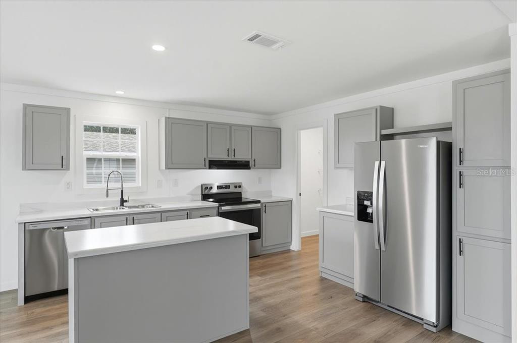 9128 Scepter Avenue Brooksville, FL 34613 - Photo 3 of 44 a kitchen with a refrigerator a sink a stove a microwave and cabinets