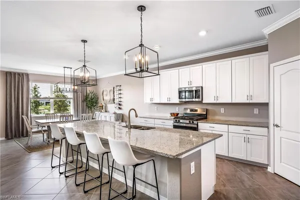 a kitchen with stainless steel appliances granite countertop a sink a stove a kitchen island with chairs and cabinets