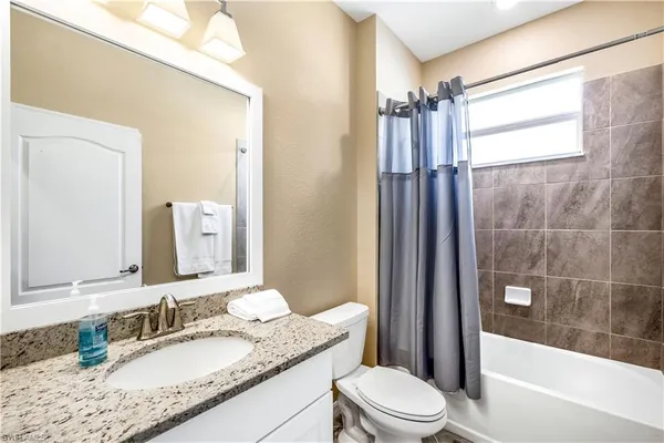 a bathroom with a granite countertop sink toilet mirror and shower