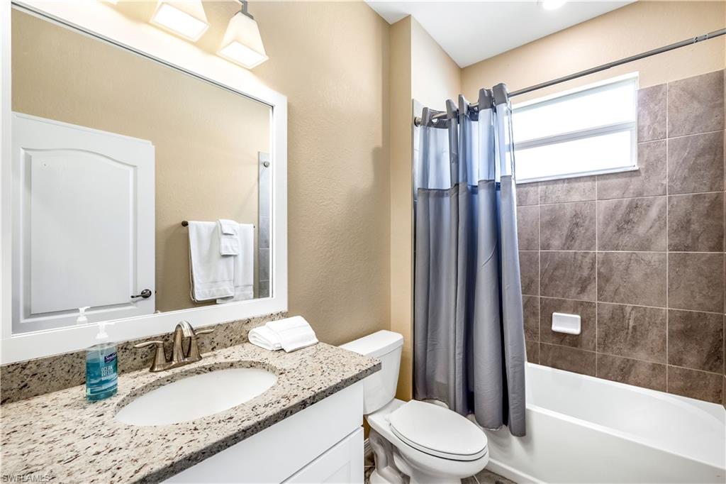 43693 Tree Top Trail Babcock Ranch, FL 33982 - Photo 18 of 25 a bathroom with a granite countertop sink toilet mirror and shower
