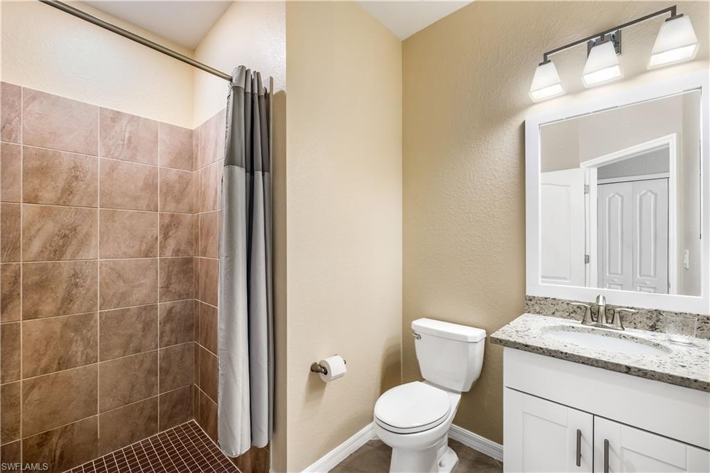 43693 Tree Top Trail Babcock Ranch, FL 33982 - Photo 21 of 25 a bathroom with a granite countertop sink a toilet and shower