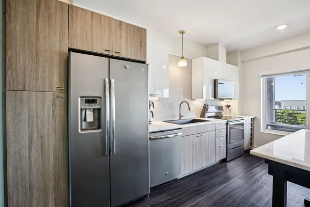 a kitchen with granite countertop a stove a sink and a refrigerator
