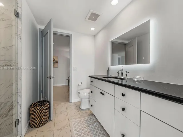 a bathroom with a granite countertop sink mirror and toilet