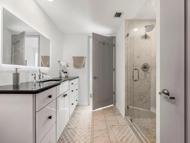 a bathroom with a granite countertop shower sink and mirror