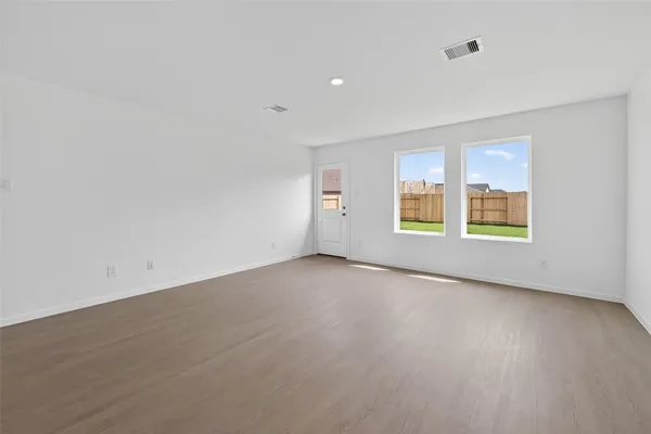 a view of an empty room with a window and wooden floor