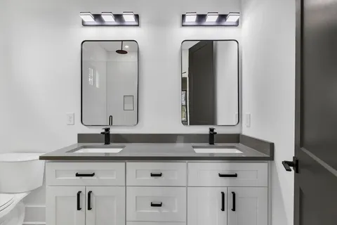 a bathroom with double vanity sinks and a mirror