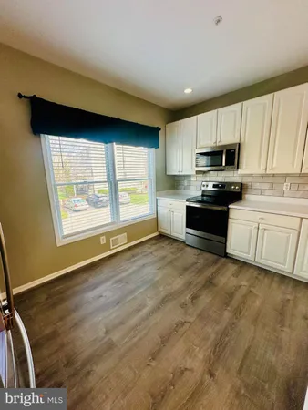 a kitchen with granite countertop a refrigerator stove and white cabinets