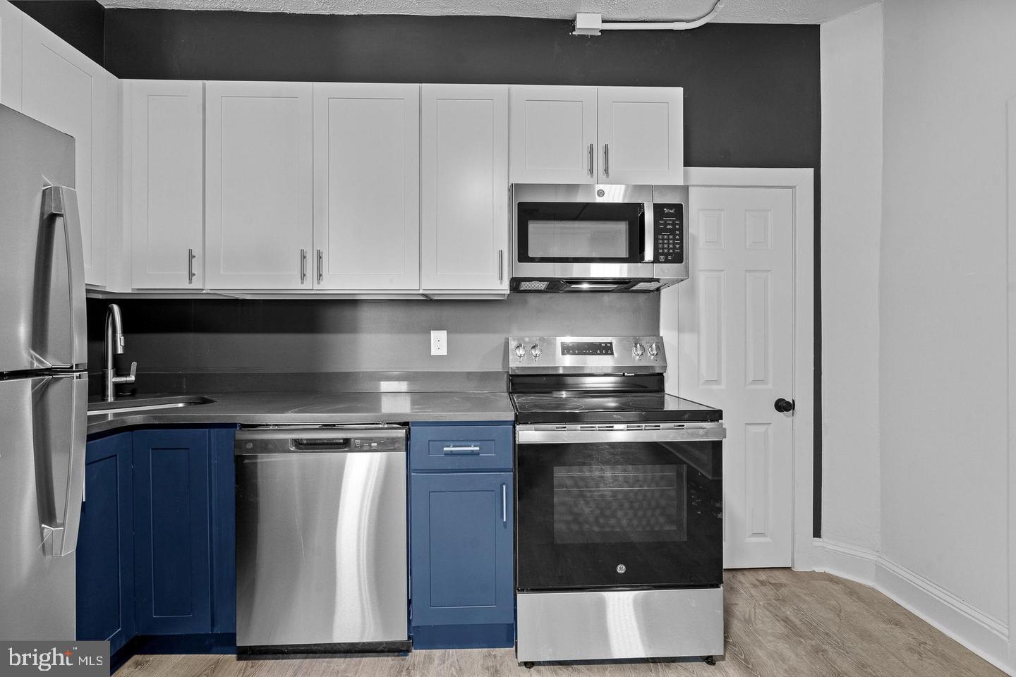 1308 West Lexington Street, Unit 3R Baltimore, MD 21223 - Photo 5 of 16 a kitchen with stainless steel appliances granite countertop a stove a microwave and a refrigerator