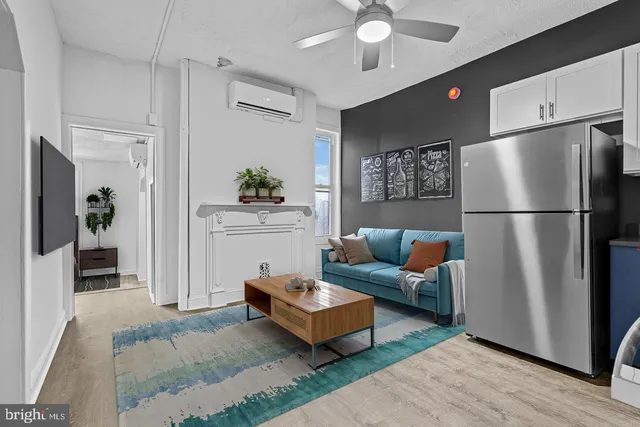 a living room with furniture and a refrigerator