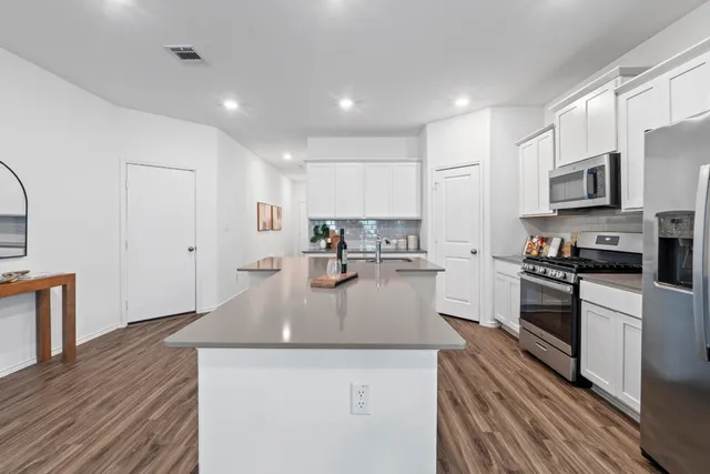 a kitchen with stainless steel appliances granite countertop a sink a stove top oven a counter space and cabinets