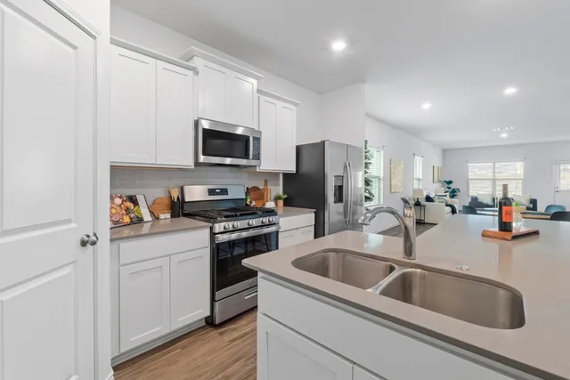 a kitchen with stainless steel appliances granite countertop a sink a stove and a refrigerator with wooden floor