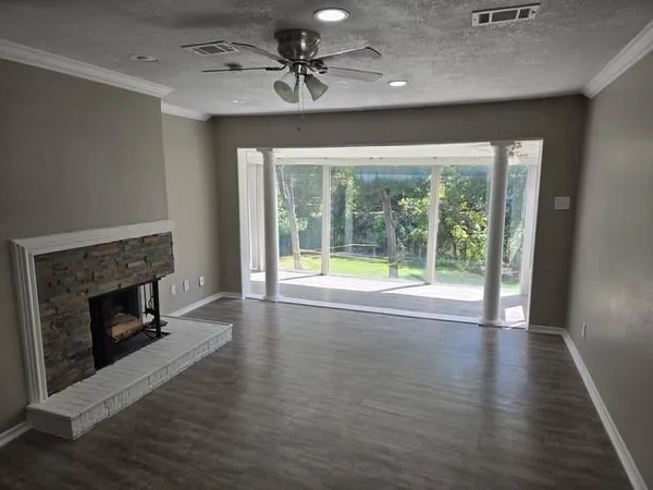 a view of an empty room with wooden floor fireplace and a window
