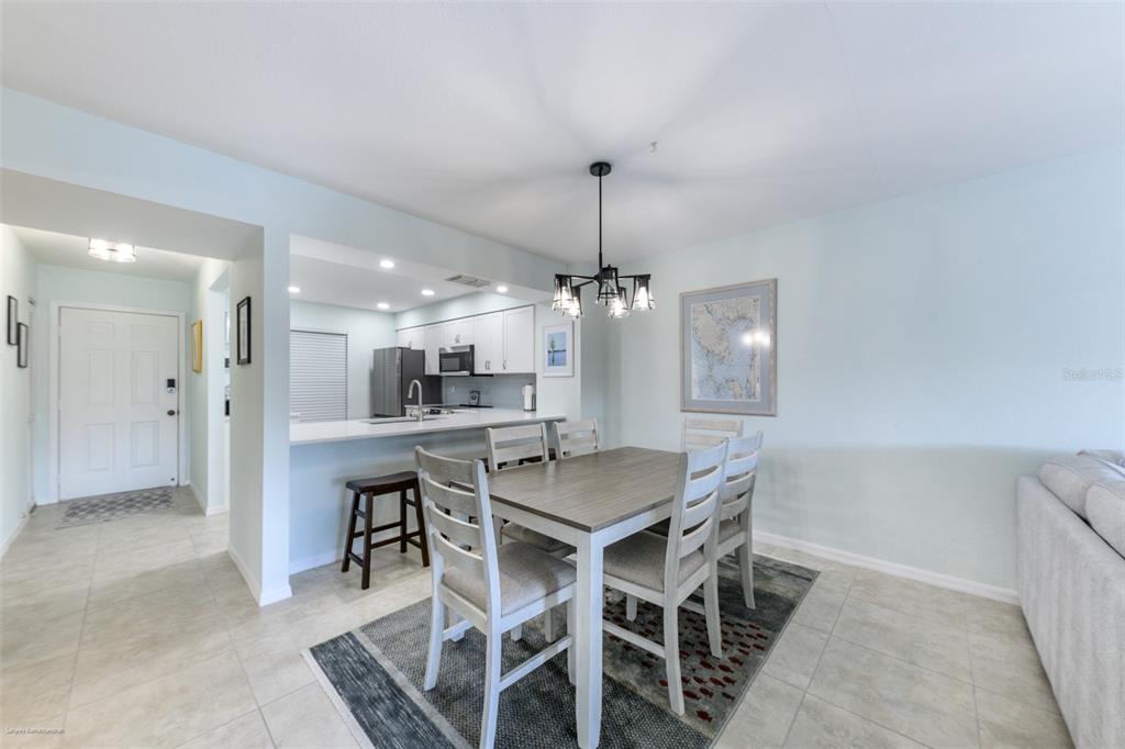 220 Coldeway Drive, Unit 112 Punta Gorda, FL 33950 - Photo 13 of 49 a dining hall with a dining table chairs wooden floor and kitchen view